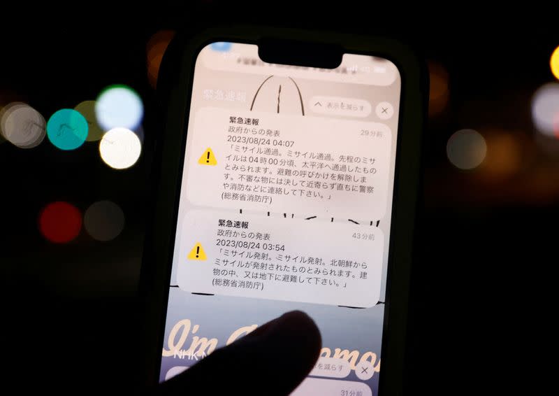 A smartphone screen shows J-Alert warning messages regarding North Korea appeared to have fired a missile in Chatan, Okinawa