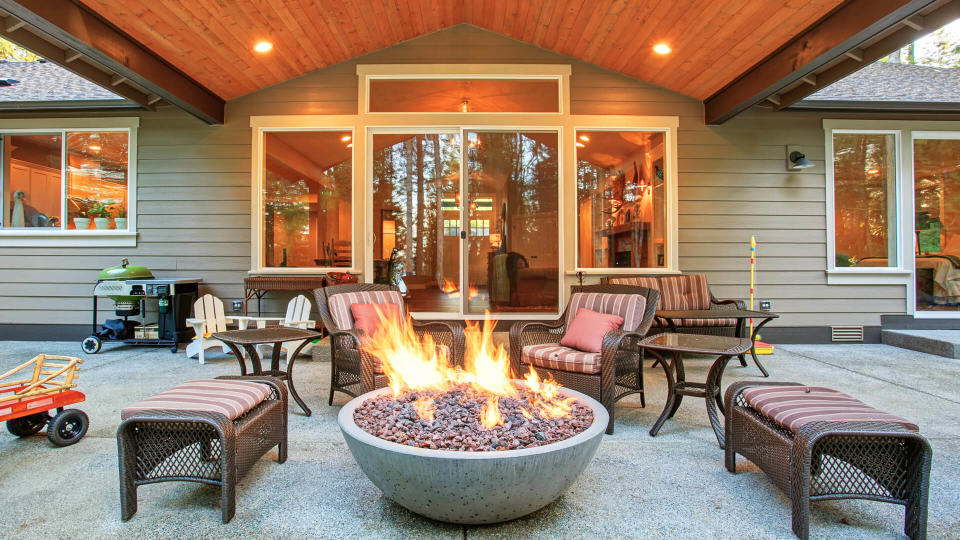Large back yard with grass and covered patio with firepit.