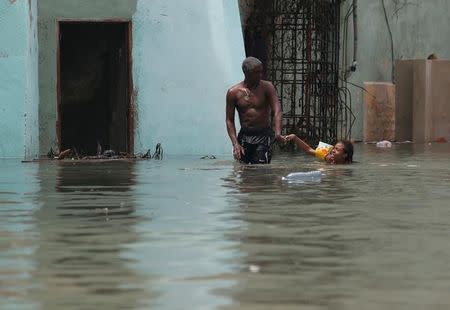 A man helps a girl with a swim float as she plays in a flooded street, after the passing of Hurricane Irma, in Havana, Cuba September 10, 2017. REUTERS/Stringer