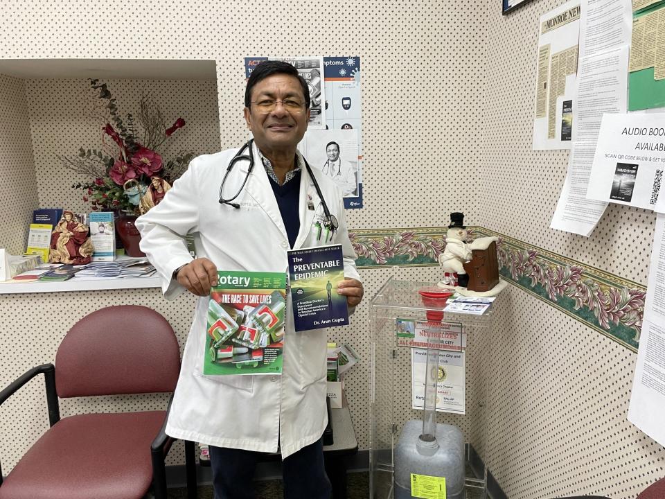 Monroe addiction physician Dr. Arun Gupta is shown in his Monroe office holding copies of his 2022 book and this month's "The Rotarian." Gupta is featured in the magazine's cover story about the opioid crisis.
