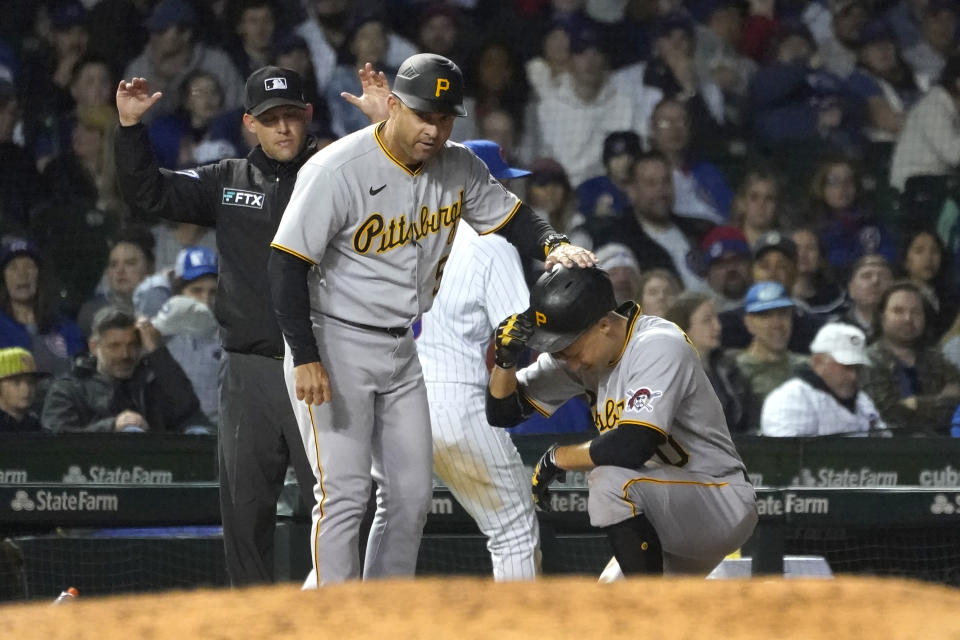 Pittsburgh Pirates third base coach Mike Rabelo, left, pats Bryan Reynolds on the helmet after his triple against the Chicago Cubs during the seventh inning of a baseball game Thursday, April 21, 2022, in Chicago. (AP Photo/Charles Rex Arbogast)