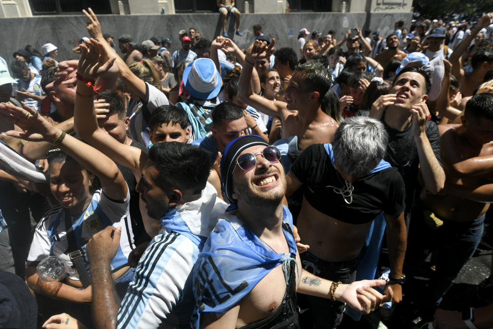 Soccer fans look up for water thrown by residents in Buenos Aires, Argentina Tuesday, Dec. 20, 2022. Fans descended into the streets of the capital eager to catch a glimpse of the open-top bus carrying the Argentine national soccer team that won the World Cup final. (AP Photo/Mario De Fina)