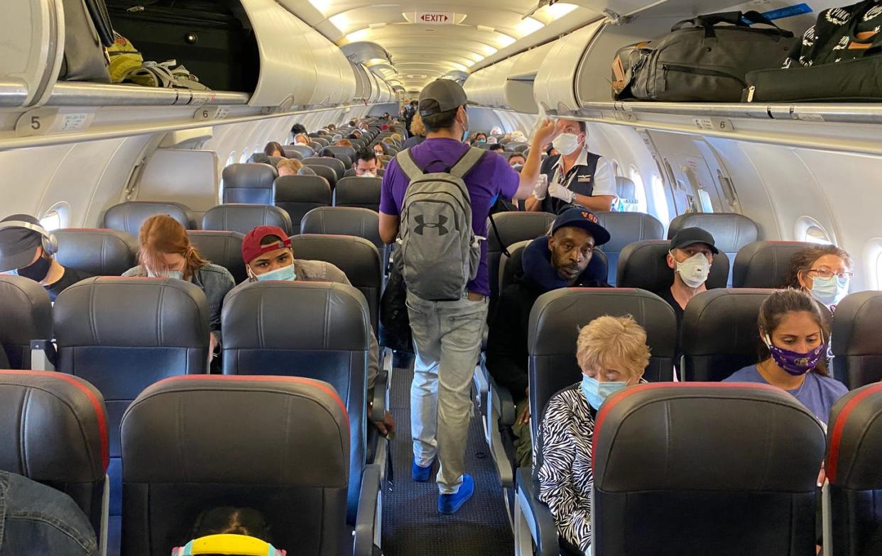 <span class="caption">Passengers board a plane in New York City on May 3, 2020. Air travel from such hot spots did not lead to surges to other cities, a study suggests.</span> <span class="attribution"><a class="link " href="https://www.gettyimages.com/detail/news-photo/passengers-almost-all-wearing-facemasks-board-an-american-news-photo/1213388331?adppopup=true" rel="nofollow noopener" target="_blank" data-ylk="slk:Eleonore Sens/AFP via Getty Images);elm:context_link;itc:0;sec:content-canvas">Eleonore Sens/AFP via Getty Images)</a></span>
