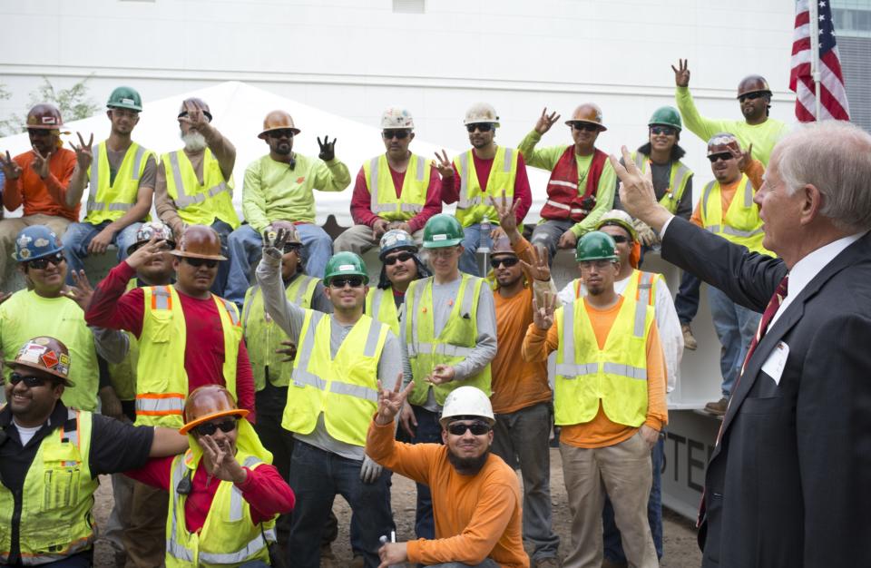 Leo Beus, right,  gives the "forks up" sign for ASU before the final beam is lifted into place, June 9, 2015. Leo and Annette Beus donated $10 million toward construction of the law school.