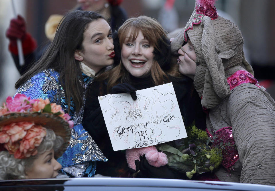 Actor Bryce Dallas Howard, center, Hasty Pudding Woman of the Year, is kissed by Harvard University theatrical students Grace Ramsey, left, and David Lynch, right, as they ride in the back of a convertible during a parade, Thursday, Jan. 31, 2019 through Harvard Square, in Cambridge, Mass. The award was presented to Howard by Hasty Pudding Theatricals, a theatrical student society at Harvard University. (AP Photo/Steven Senne)