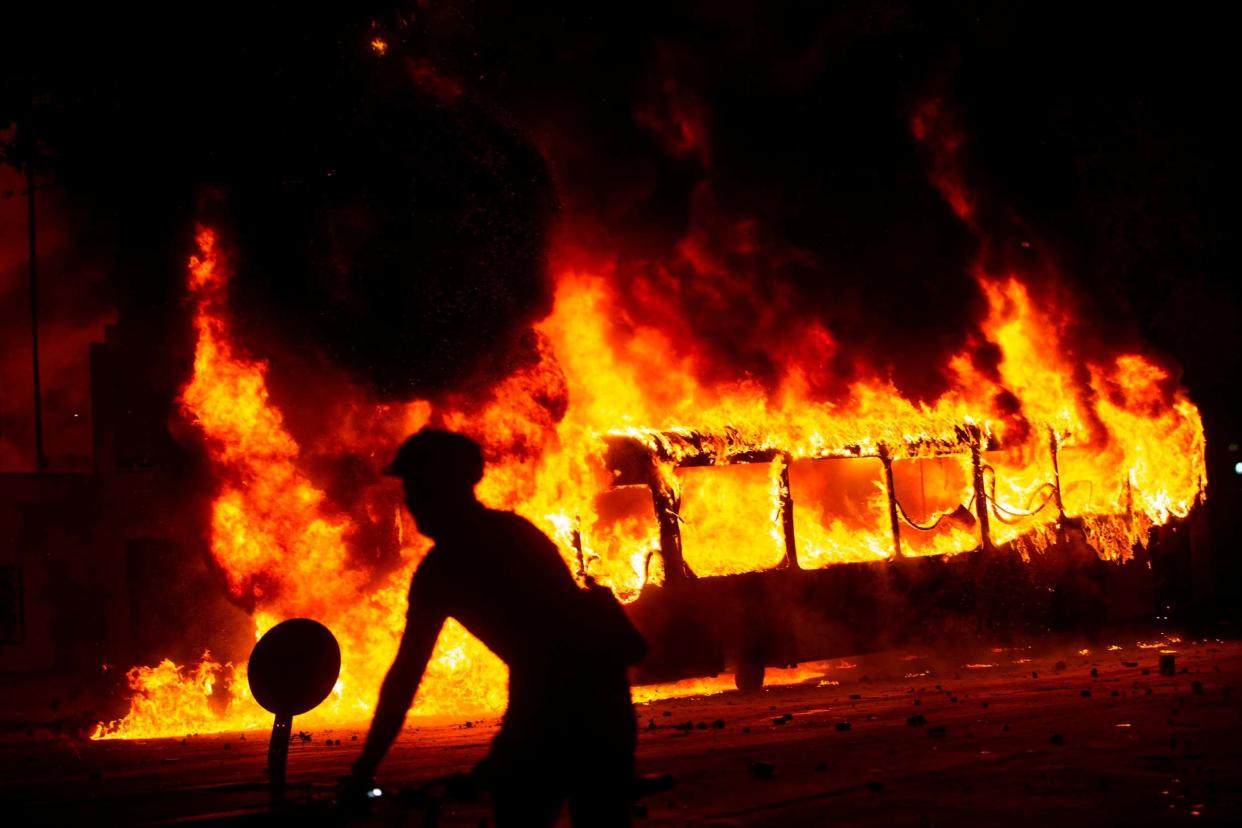 A bus burns down in Santiago on Thursday amid mass fare-dodging protests: AFP via Getty Images