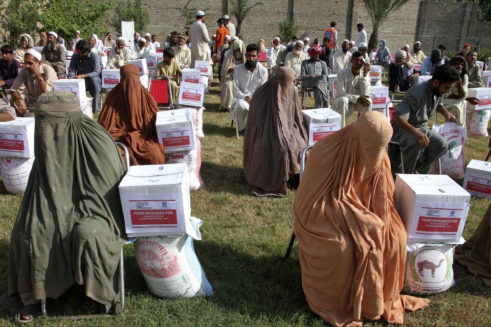 Volunteers from the religious charity group Al-Khidmat Foundation Pakistan distribute food and other items to flood-affected families, in Shabqadar near Peshawar, Pakistan, Tuesday, Sept. 13, 2022. Pakistan is grappling with food shortages after deadly floods left the impoverished country's agriculture belt underwater as authorities scaled up efforts to deliver food, tents and other items. (AP Photo/Muhammad Sajjad)