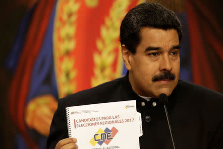 Venezuela's President Nicolas Maduro shows a book that reads "Candidates for 2017 regional elections" during a news conference at Miraflores Palace in Caracas, Venezuela August 22, 2017. REUTERS/Marco Bello