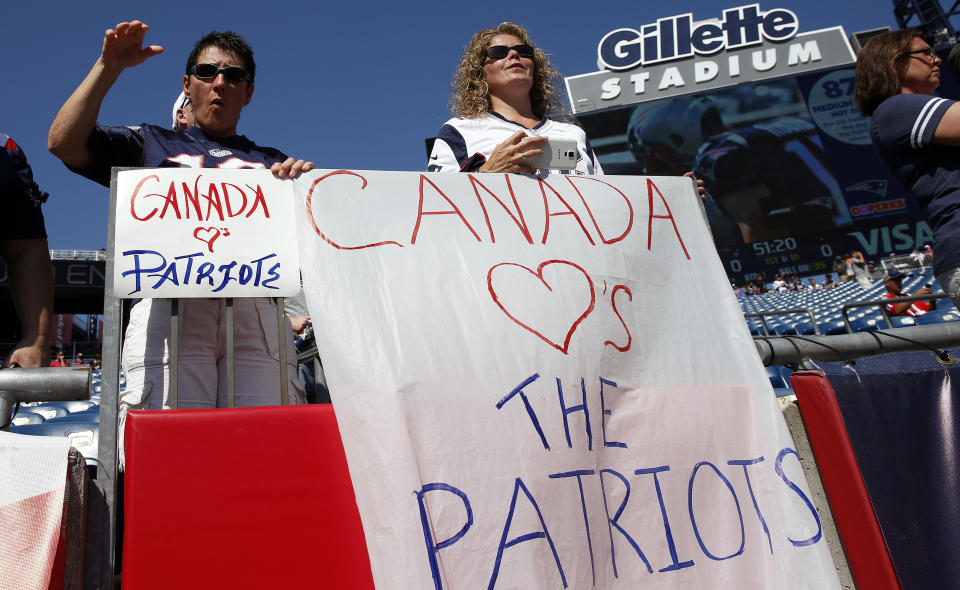 New England Patriots fans hold signs referring to Canada before an NFL football game between the Patriots and the Houston Texans. (AP)