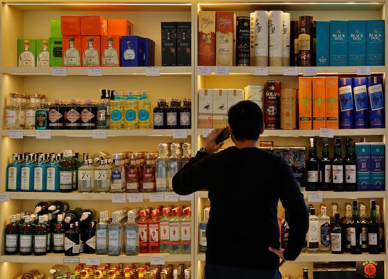 A customer looks at liquor bottles for purchase at a liquor store in Gurugram