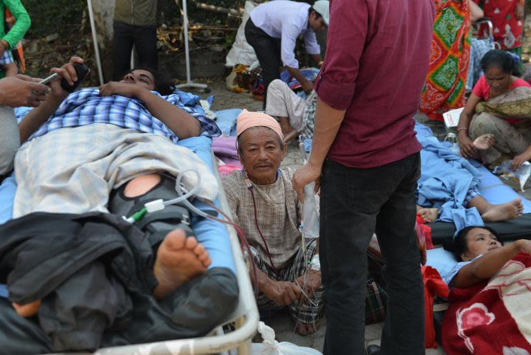 Nepalese patients lie on stretchers in an open area after being carried out of a hospital building as a powerful earthquake hits Kathmandu, on May 12, 2015