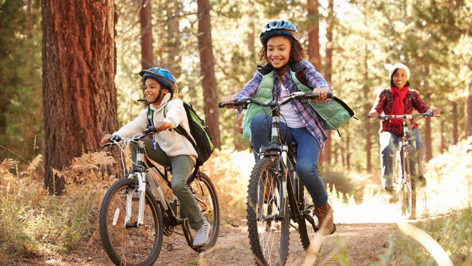 Two kids and a mom cycling on a path in the forest, to represent a tour with Thomson Family Adventures, voted one of the world's best Tour Operators