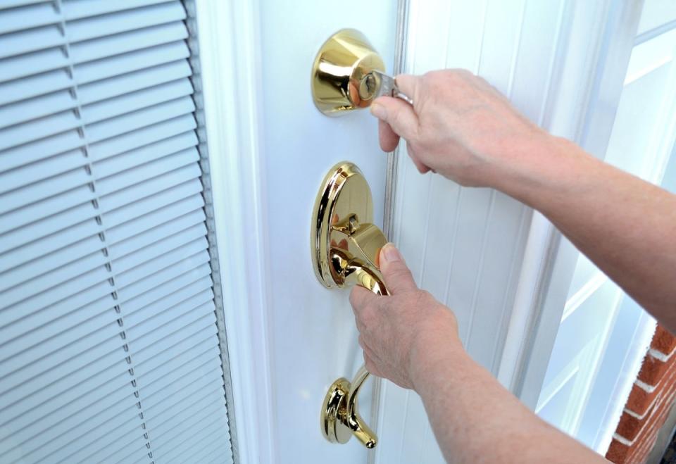 Person locking a deadbolt on an exterior door.