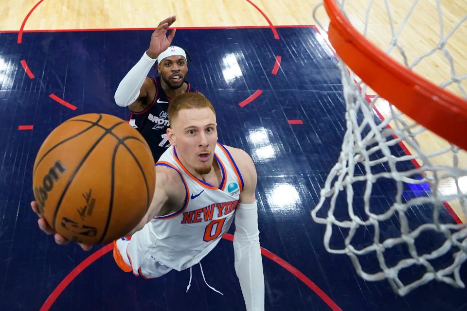 New York Knicks' Donte DiVincenzo, right, goes up for a shot past Philadelphia 76ers' Buddy Hield during the second half of an NBA basketball game, Thursday, Feb. 22, 2024, in Philadelphia.