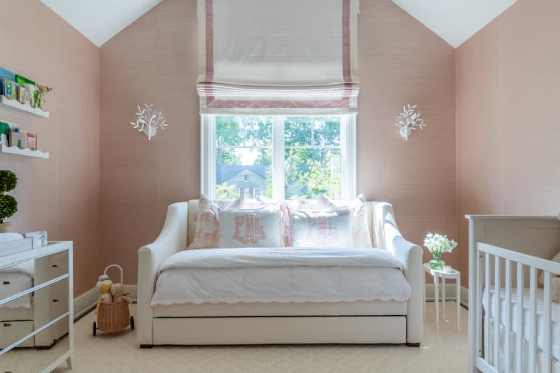 pink walls, pink and white muslin roman shades, cream loveseat, white crib, white coral inspired sconces