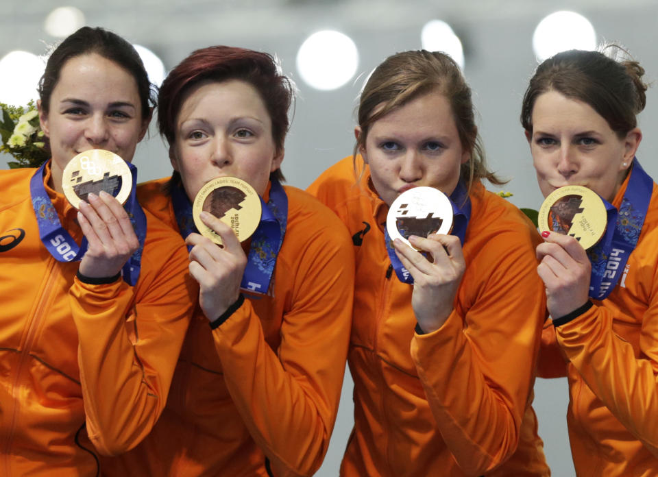Gold medallists from team Netherlands, left to right, Marrit Leenstra, Jorien ter Mors, Lotte van Beek, and Ireen Wust kiss their medals during the medal ceremony for the women's team pursuit at the Adler Arena Skating Center at the 2014 Winter Olympics, Saturday, Feb. 22, 2014, in Sochi, Russia. (AP Photo/Matt Dunham)