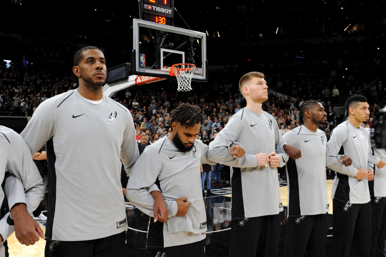 The San Antonio Spurs lock arms after the singing of the National Anthem before their season opener against the Minnesota Timberwolves. (Getty)