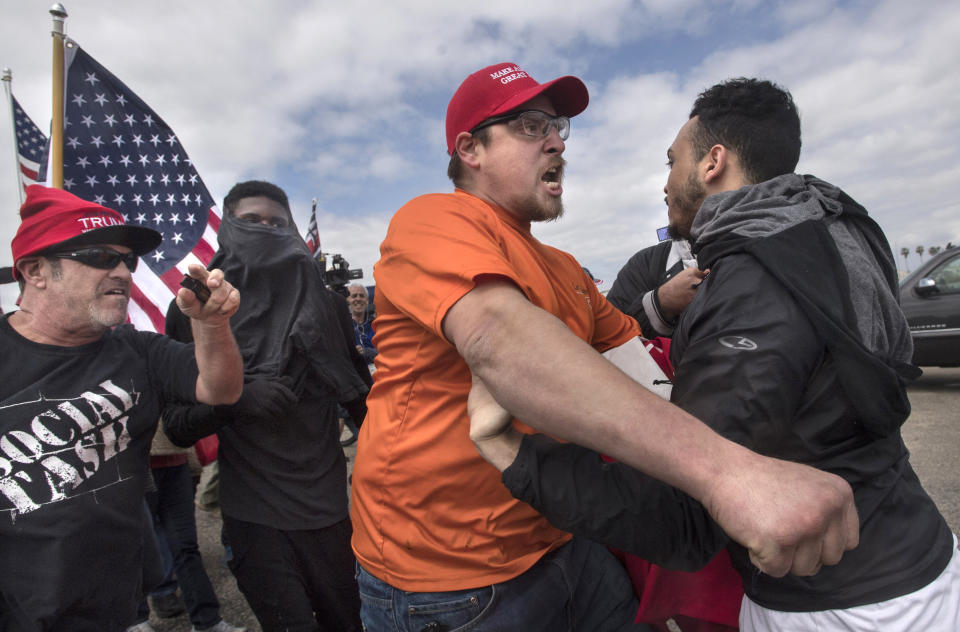 A supporter of President Donald Trump, center, clashes with an anti-Trump protester in Huntington Beach, Calif., on Saturday, March 25, 2017. Counter-protesters said before the march began that they planned to try to stop the march's progress with a "human wall." (Mindy Schauer/The Orange County Register via AP)