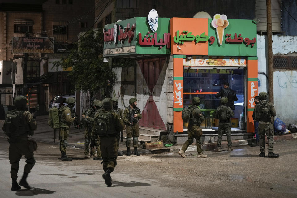 Israeli soldiers are deployed at the scene where a Palestinian gunman opened fire at soldiers in the West Bank town of Hawara, Saturday, March 25, 2023. The Israeli military said two soldiers were wounded Saturday evening in a drive-by shooting in the occupied West Bank, the latest in months-long violence between Israel and the Palestinians. The attack was the third to take place in the Palestinian town of Hawara in less than a month. A manhunt was launched as forces sealed roads leading to Hawara. (AP Photo/Majdi Mohammed)
