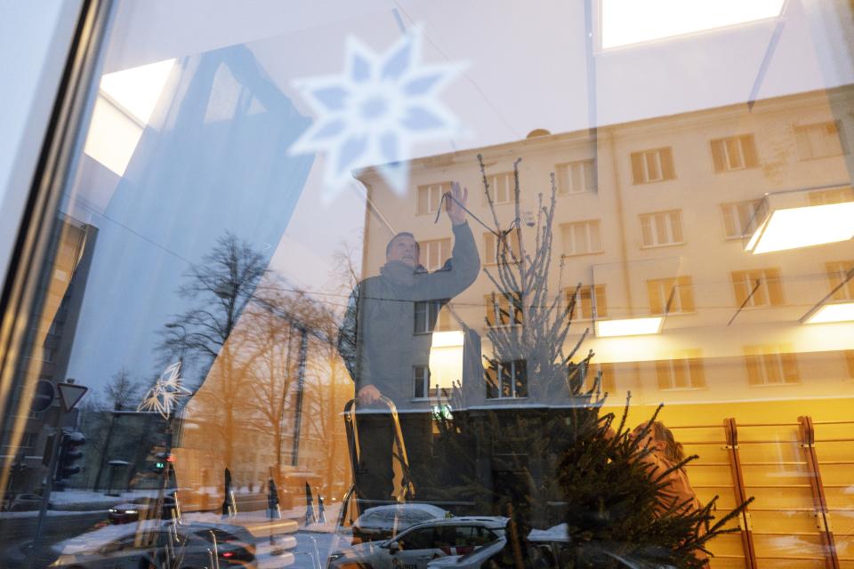 Arvo Palumae, co-owner of a Christmas tree farm, sets a spruce in a hall of a kindergarten in Tallinn, Estonia, Tuesday, Dec. 12, 2023. In Estonia, as in many parts of the world, trees covered with lights brighten up homes and town squares during the Winter Solstice and Christmas festivities afterwards. (AP Photo/Pavel Golovkin)