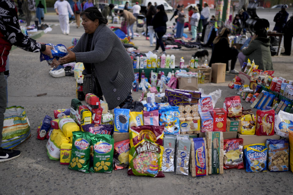 Una vendedora completa una transacción en un mercado donde la gente puede comprar o intercambiar bienes, en las afueras de Buenos Aires, Argentina, el miércoles 10 de agosto de 2022. (AP Foto/Natacha Pisarenko)