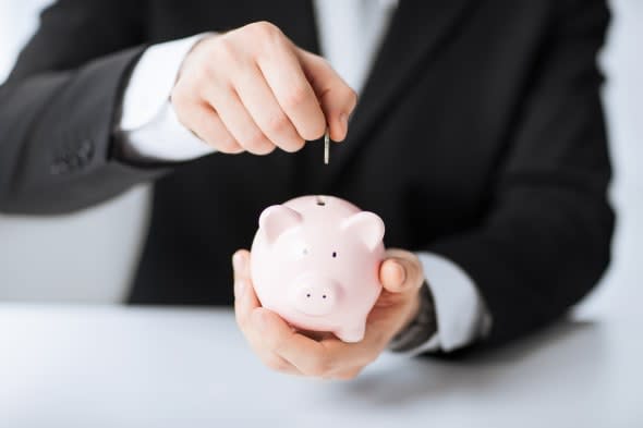 picture of man putting coin into small piggy bank