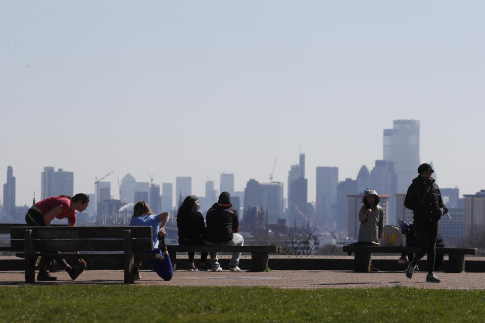 Pedestrians walk on Primrose Hill with the skyline of central London as a backdrop in London, Monday, March 23, 2020. The British government is encouraging people to practice social distancing to help prohibit the spread of Coronavirus, further restrictions may be imposed if the public do not adhere to their advice. For most people, the new coronavirus causes only mild or moderate symptoms, such as fever and cough. For some, especially older adults and people with existing health problems, it can cause more severe illness, including pneumonia. (AP Photo/Frank Augstein)