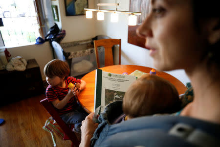 Amanda Gries holds her previous home's Lead-Based Paint Inspection/Risk Assessment and her 12-month-old son Eli Gries while her three and a half year old son Wyatt (L) sits at a table in their home in the Del Rey neighborhood of Los Angeles, California, United States April 4, 2017. REUTERS/Danny Moloshok