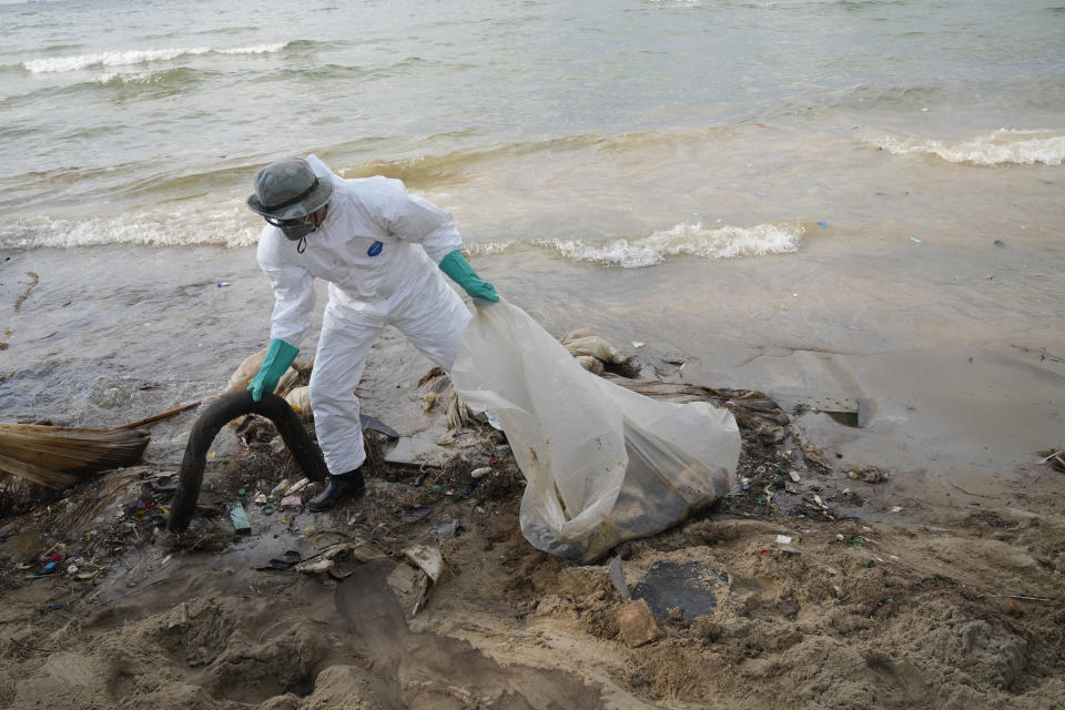 Workers carry out a cleanup operation on Mae Ramphueng Beach after a pipeline oil spill off the coast of Rayong province in eastern Thailand, Sunday, Jan. 30, 2022. The governor of a province in eastern Thailand on Saturday declared a state of emergency after an oil slick washed up on a sand beach, shutting down restaurants and shops in a setback for the pandemic-hit tourism industry. (AP Photo/Sakchai Lalit)