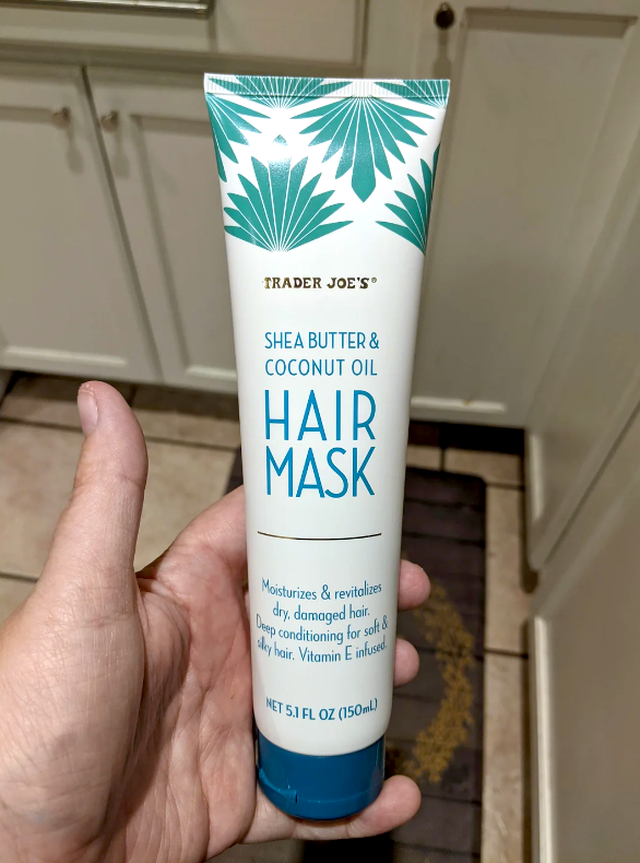 Person holding a Trader Joe's Hair Mask tube with shea butter and coconut oil