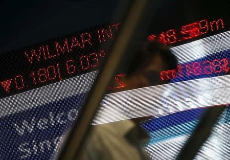 A man passes a stock index board showing Wilmar International losing 6.03 percent at the Singapore Exchange in the central business district August 24, 2015. REUTERS/Edgar Su/Files