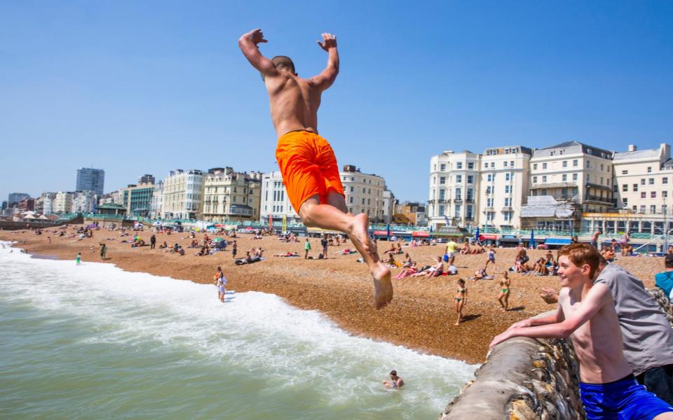 Children can be seen jumping of the pontoon in the sea in Brighton and Hove - LNP 