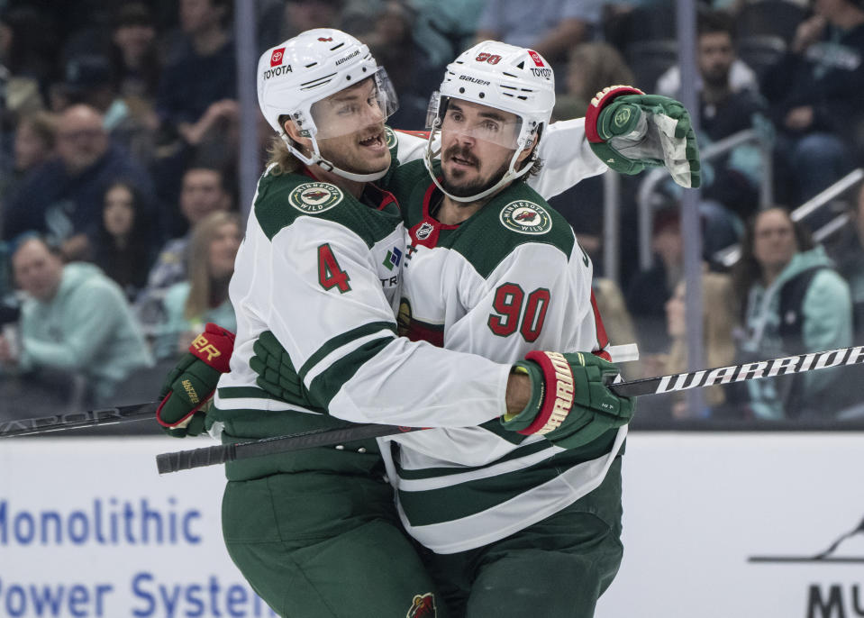 Minnesota Wild forward Marcus Johansson, right, celebrates with defenseman Jon Merrill, left, after scoring against the Seattle Kraken during the first period of an NHL hockey game, Saturday, Feb. 24, 2024, in Seattle. (AP Photo/Stephen Brashear)