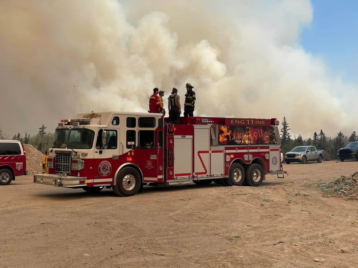 Crew members stand on a fire engine near a wildfire burning out of control in Shelburne County last week. A 50-50 draw that raises funds for firefighters in Nova Scotia topped $1.2 million last week. (Troy K. Stoddard - image credit)