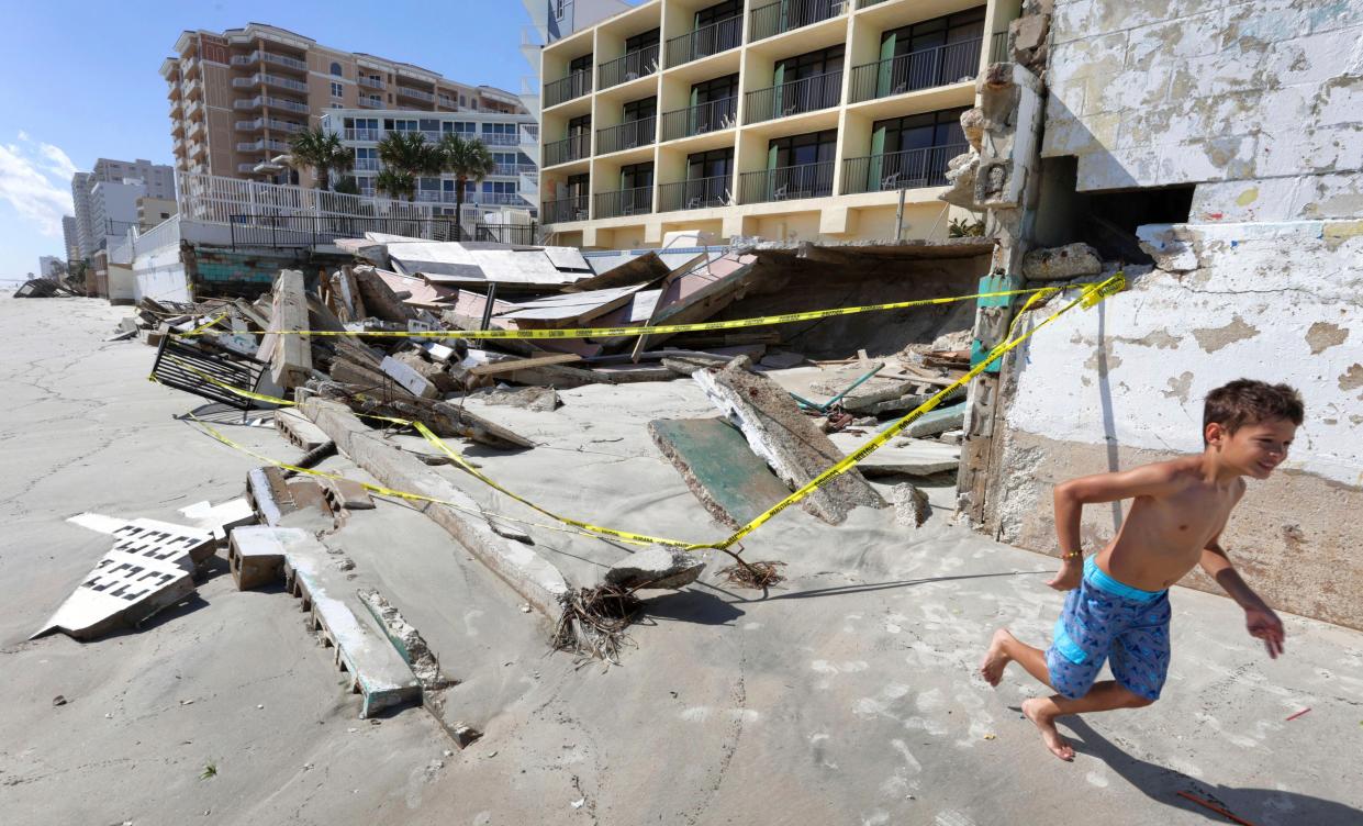 A boy runs past a collapsed pool deck Monday, Oct. 3, 2022, in Daytona Beach Shores, Fla., as hotel and condo seawalls and decks along the Volusia County coastline were gutted by Hurricane Ian last week. 