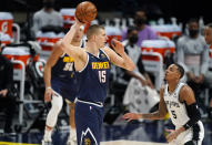 Denver Nuggets center Nikola Jokic, front left, looks to pass the ball as San Antonio Spurs guard Dejounte Murray, right, defends in the first half of an NBA basketball game Friday, April 9, 2021, in Denver. (AP Photo/David Zalubowski)