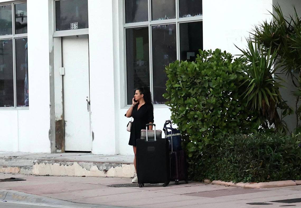 A woman waits with her luggage outside the evacuated Port Royale Condominium located at 6969 Collins Ave. on Thursday, Oct. 27, 2022.