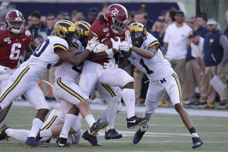 Alabama running back Najee Harris (22) fights for extra yardage as Michigan defensive back Daxton Hill, left, linebacker Jordan Glasgow, second from left, and defensive back Ambry Thomas (1) try to stop him during the second half of the Citrus Bowl NCAA college football game, Wednesday, Jan. 1, 2020, in Orlando, Fla. (AP Photo/John Raoux)