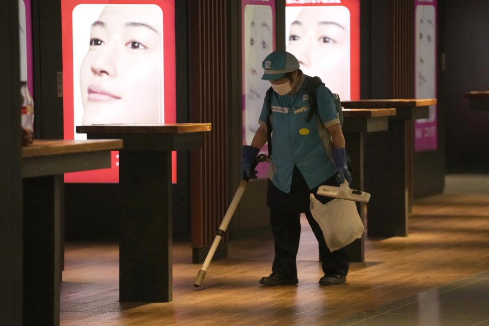 An employee wearing a protective mask to help curb the spread of the coronavirus cleans the floor at the underneath of a subway station Thursday, July 29, 2021, in Tokyo. (AP Photo/Eugene Hoshiko)