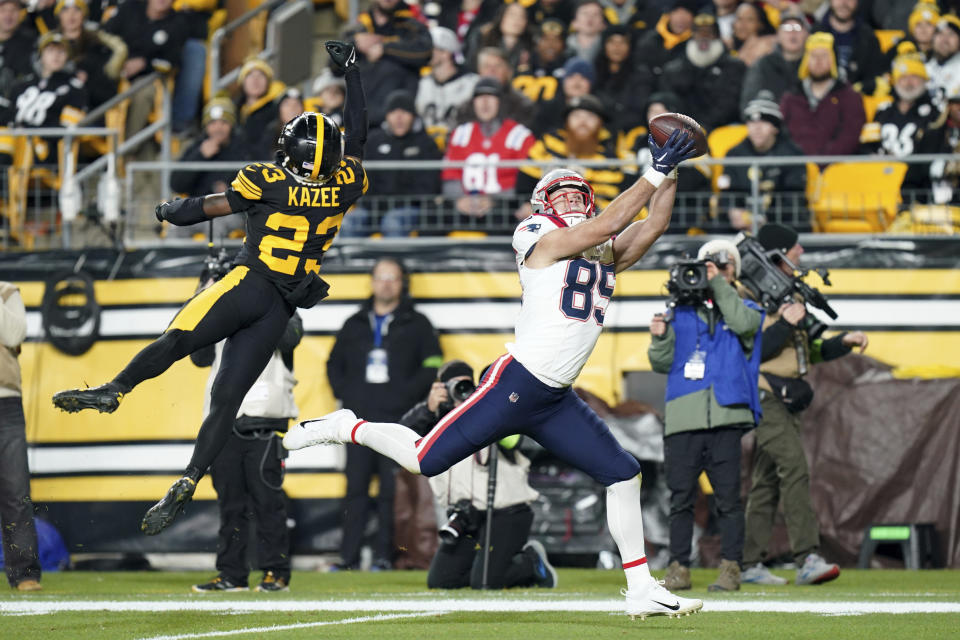 New England Patriots tight end Hunter Henry (85) catches a touchdown pass as Pittsburgh Steelers safety Damontae Kazee (23) defends during the first half of an NFL football game on Thursday, Dec. 7, 2023, in Pittsburgh. (AP Photo/Matt Freed)