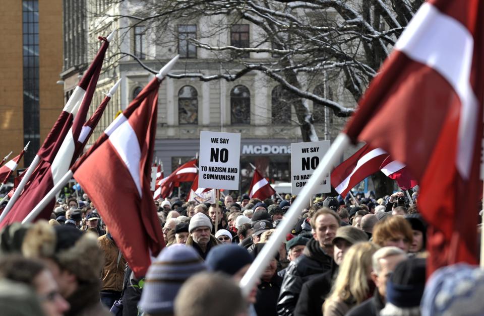 People carry Latvian flags as they march to the Freedom Monument to commemorate World War II veterans who fought in Waffen SS divisions, in Riga, Latvia, Sunday, March 16, 2014. People participate in annual commemorations of Latvian soldiers who fought in Nazi units during WWII. (AP Photo/Roman Kosarov, F64 Photo Agency)