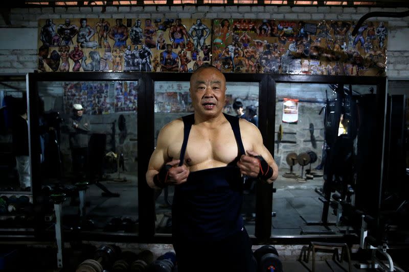 Xu Wei, a 63-year-old former factory worker and the current gym manager, show his muscles at the gym which has been turned from a bicycle shed inside a residential compound in the southwest of Beijing