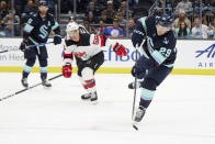 Seattle Kraken defenseman Vince Dunn (29) passes the puck with New Jersey Devils left wing Erik Haula (56) behind during the first period of an NHL hockey game, Thursday, Jan. 19, 2023, in Seattle. (AP Photo/John Froschauer)