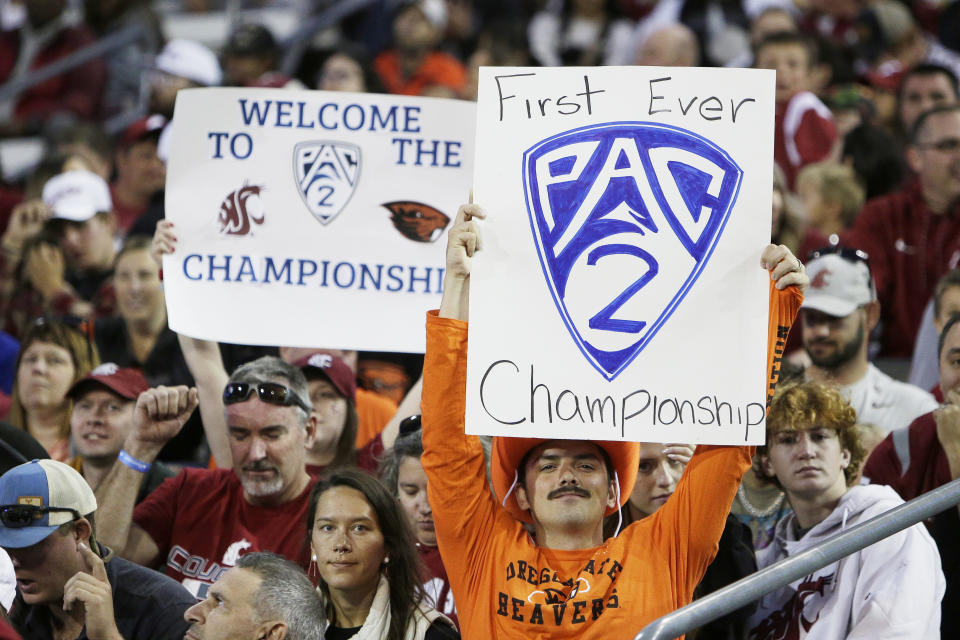 FILE - An Oregon State fan, front, and a Washington State fan hold "Pac-2" signs, representing the two schools that will remain in the Pac-12 after the 2023-2024 academic year after the other schools in the conference announced plans to leave, during the second half of an NCAA college football game, Saturday, Sept. 23, 2023, in Pullman, Wash. (AP Photo/Young Kwak, File)