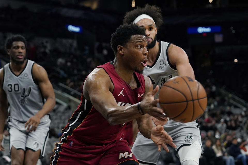Miami Heat guard Kyle Lowry, center, drives around San Antonio Spurs guard Derrick White, right, during the first half of an NBA basketball game, Thursday, Feb. 3, 2022, in San Antonio. (AP Photo/Eric Gay)