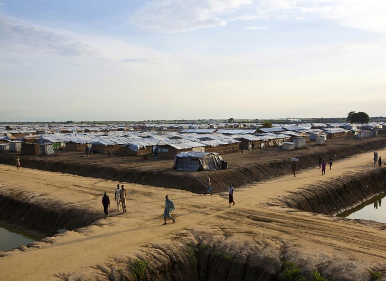 People walk through the United Nations base outside Bentiu, which hosts around 118,000 people uprooted during the country's 21-month old civil war