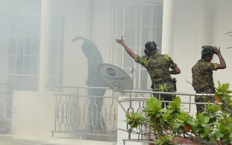 Sri Lankan Special Task Force (STF) personnel gesture outside a house during a raid - Credit: ISHARA S. KODIKARA/AFP