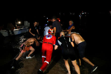 Rescuers and volunteers push an inflatable boat as locals are evacuated during a wildfire at the village of Mati, near Athens, Greece, July 23, 2018. REUTERS/Alkis Konstantinidis