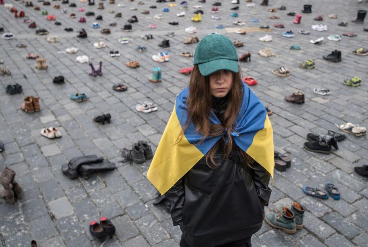 Ukrainian designer Margarita Chala stands next to shoes symbolizing war crimes committed against Ukrainian civilians at the Old Town Square in Prague in 2023. <a href="https://www.gettyimages.com/detail/news-photo/ukrainian-designer-margarita-chala-drapped-in-a-ukrainian-news-photo/1247164013?phrase=ukraine&adppopup=true" rel="nofollow noopener" target="_blank" data-ylk="slk:Michal Cizek/AFP via Getty Images;elm:context_link;itc:0;sec:content-canvas" class="link ">Michal Cizek/AFP via Getty Images</a>