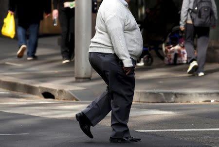 A man crosses a main road as pedestrians carrying food walk along the footpath in central Sydney, Australia, August 12, 2015. REUTERS/David Gray